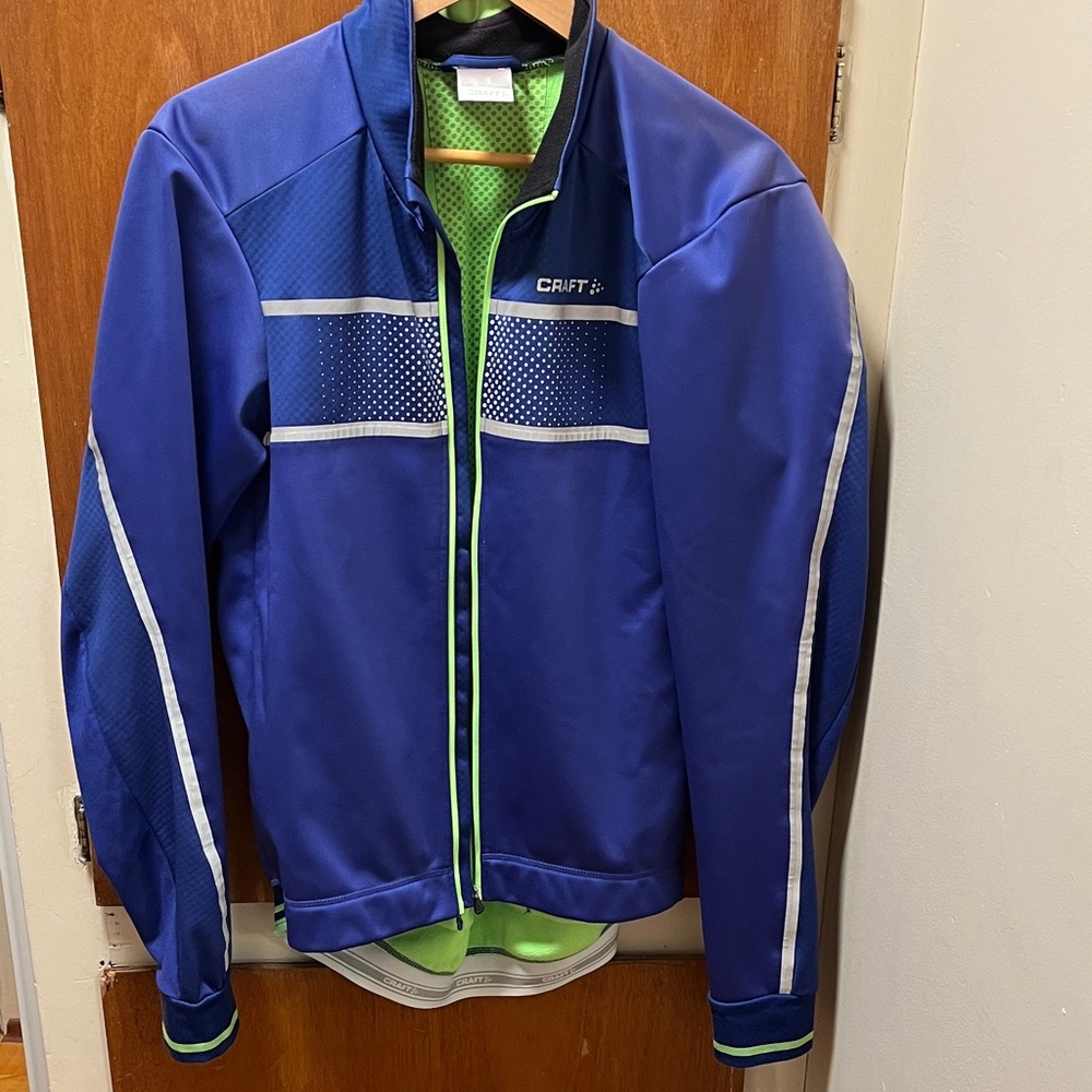 Craft Men's Purple Cycling Jacket with Green Inner and Reflective Accents.